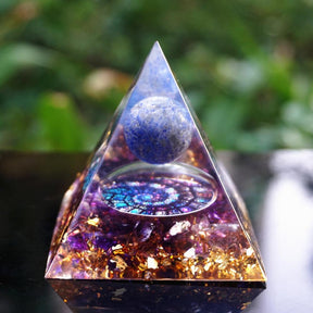 Fibonacci-inspired lapis lazuli orgone pyramid with a blue sphere, spiral inlay and purple amethyst layers. Standing upright outdoors, showing the clear pointed tip and layered base.