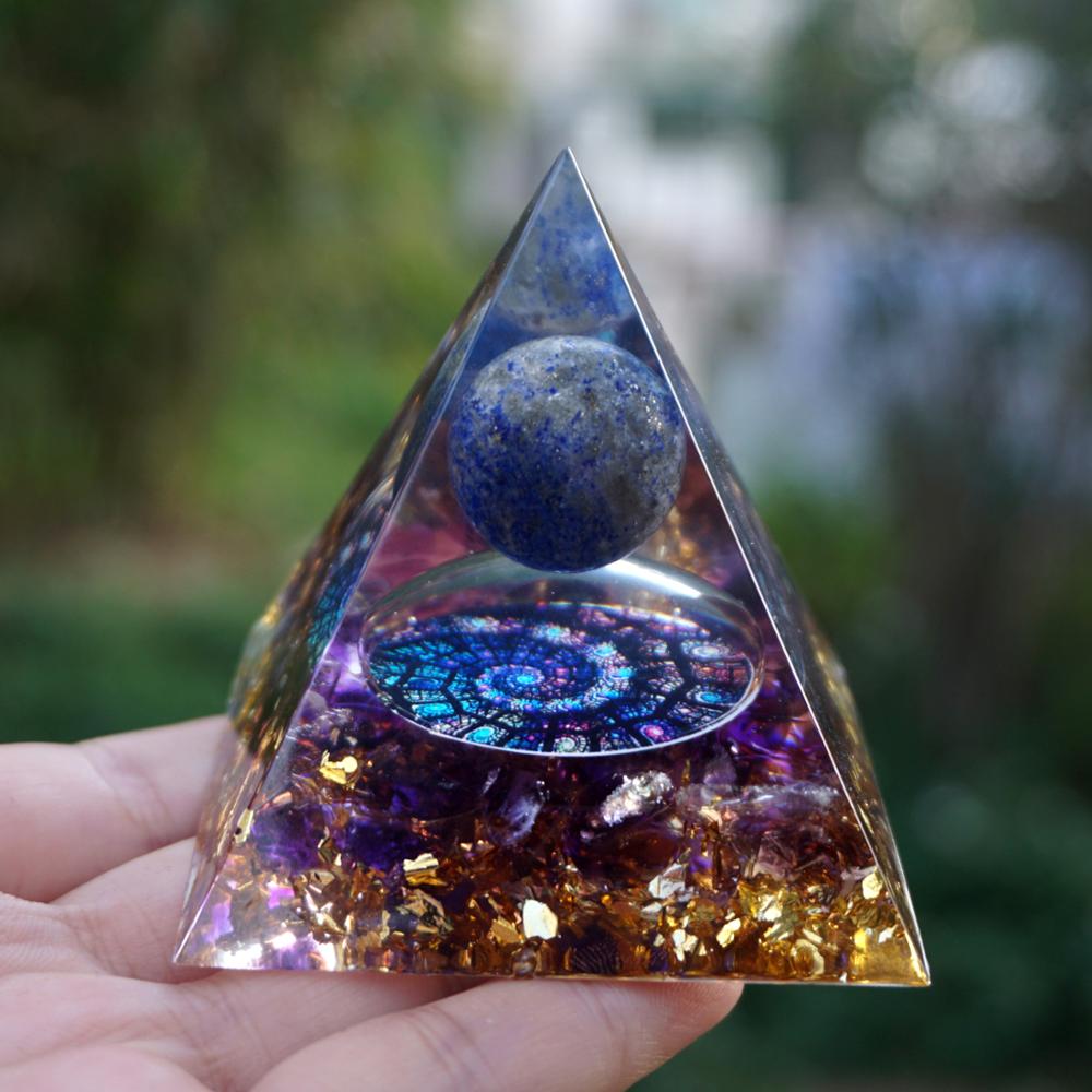 Fibonacci-inspired lapis lazuli orgone pyramid with a blue sphere, spiral inlay and purple amethyst layers. Upright palm view with the blue sphere, copper-coloured outline and purple lower layer.