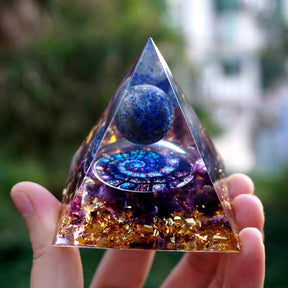 Fibonacci-inspired lapis lazuli orgone pyramid with a blue sphere, spiral inlay and purple amethyst layers. Front view showing the nautilus-style circular artwork beneath the blue sphere.