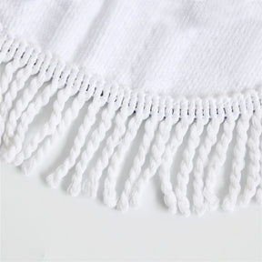 Close-up of white knotted fringe along the edge of the floral skull rug fabric.