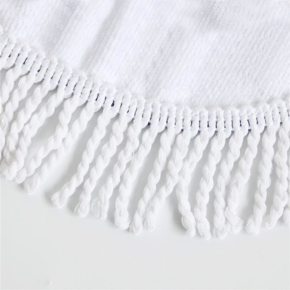 Close-up of white knotted fringe along the edge of the floral skull rug fabric.