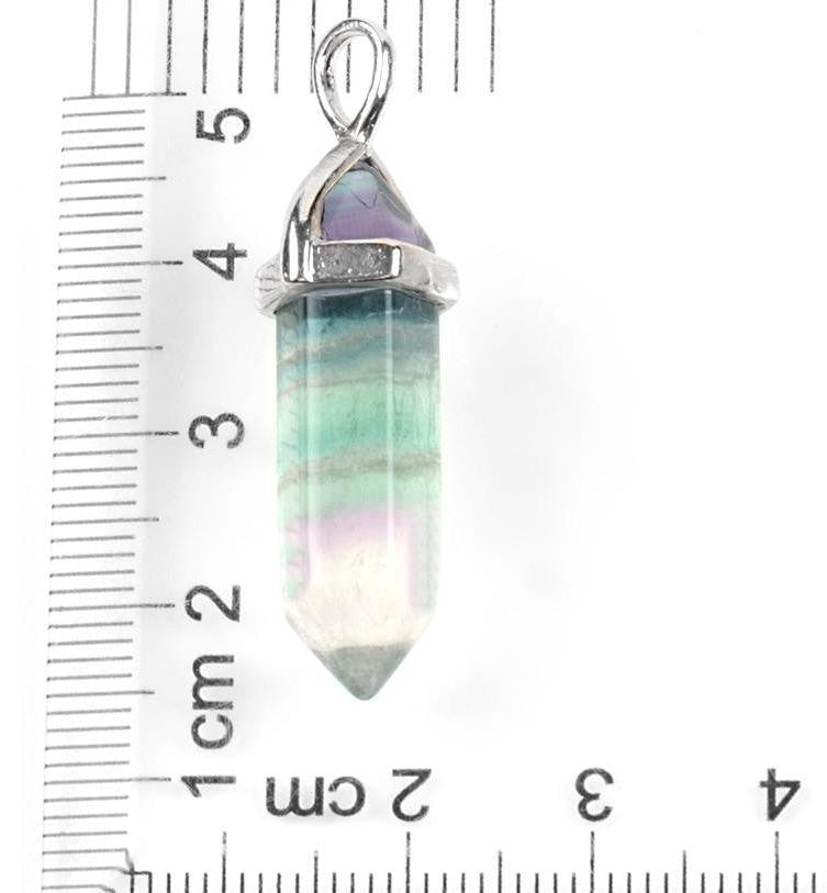 Fluorite pendant beside a ruler, showing the pointed stone and silver-tone cap for scale.