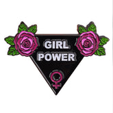 Black triangle Girl Power enamel pin with white lettering, pink roses, green leaves and a pink Venus symbol, shown against a white background.