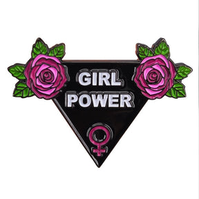 Black triangle Girl Power enamel pin with white lettering, pink roses, green leaves and a pink Venus symbol, shown against a white background.