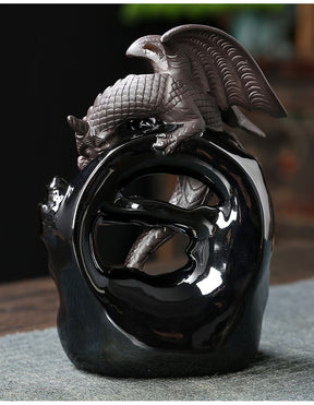 Wider rear view of the gothic dragon incense burner, showing the raised wings and curved body silhouetted above its glossy black base.