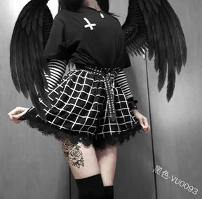 Fuller front view of the black-and-white grid skort, styled with a dark top and belt. The angled white lines follow the folds above a soft black lace edge.
