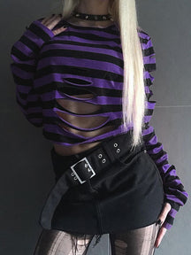 Purple and black striped crop sweater styled with a black skirt, showing the large horizontal front cutouts and long sleeves.