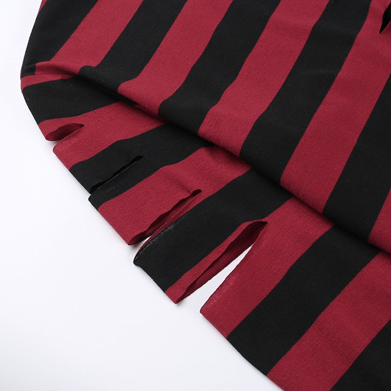 Detail of the cutout sections along the red and black striped sweater's upper sleeve.