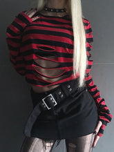 Closer front view of the red and black ripped crop sweater above a black skirt, with a choker and long pale hair completing the outfit.