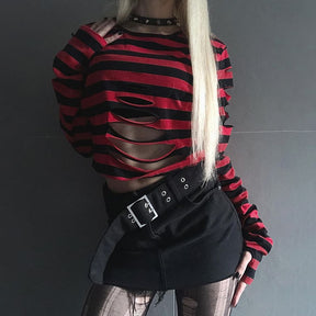 Red striped gothic crop sweater shown with one hand resting by a wide black belt, highlighting the curved openings across the front.