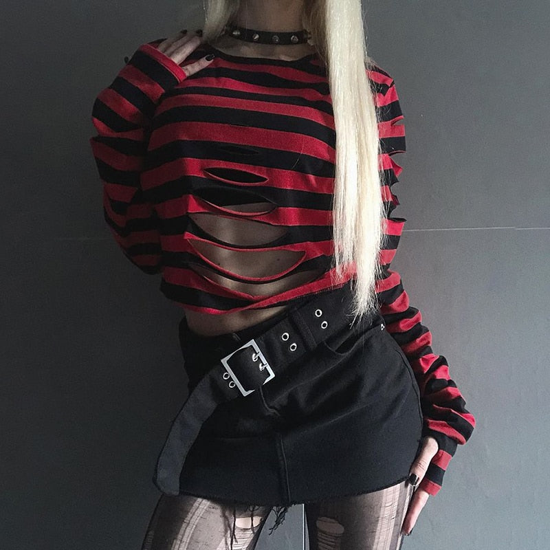Red striped gothic crop sweater shown with one hand resting by a wide black belt, highlighting the curved openings across the front.