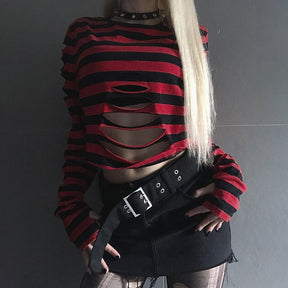 Front outfit view of the red and black striped sweater with arms lowered, showing the long sleeves and open slashes above a black mini skirt.