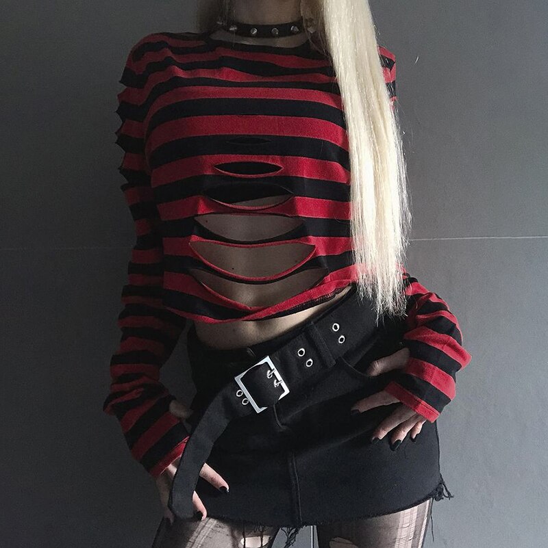 Front outfit view of the red and black striped sweater with arms lowered, showing the long sleeves and open slashes above a black mini skirt.