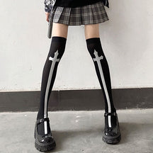 Black thigh-high stockings with tall white crosses, styled with a plaid skirt.