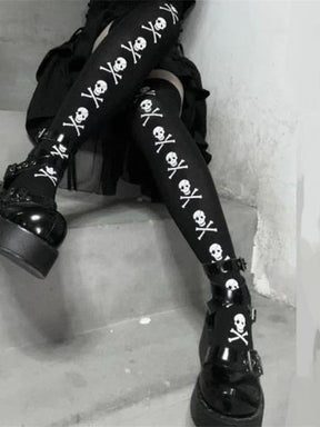 Black stockings with white skull-and-crossbones lines, shown with crossed legs on steps.