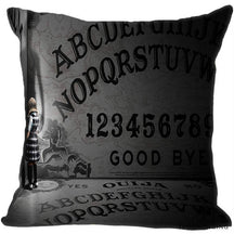Gray and black square spirit-board cushion cover with oversized alphabet rows and numbers beside a small doll figure in the printed scene.