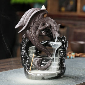 Front three-quarter view of the dragon backflow burner on a tabletop, with a cone above the wings and smoke cascading from the mouth to the base.