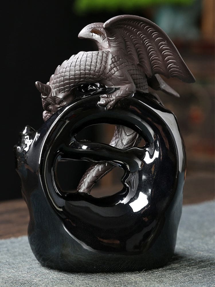 Rear view of the gray dragon incense burner, showing raised ridged wings and a scaled body perched over a glossy black open arch.