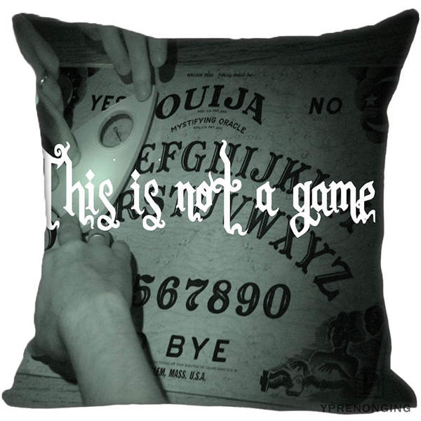 Gray square cushion cover showing hands around a printed Ouija board beneath the white phrase This is not a game.