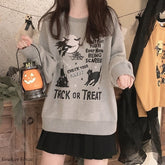 Gray Halloween crewneck sweatshirt worn with a black skirt while holding a pumpkin lantern, showing the large black Trick or Treat illustration.