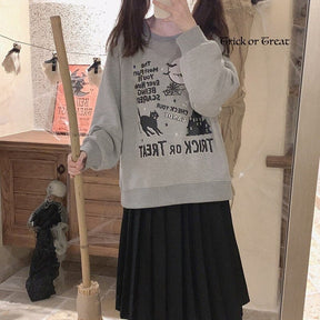 Mirror selfie of the gray Trick or Treat sweatshirt styled with a long black skirt, with the relaxed sleeves and reflected graphic visible.