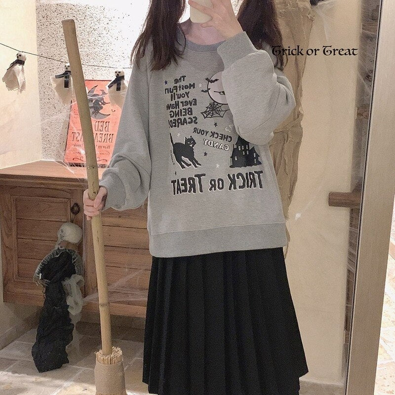 Mirror selfie of the gray Trick or Treat sweatshirt styled with a long black skirt, with the relaxed sleeves and reflected graphic visible.