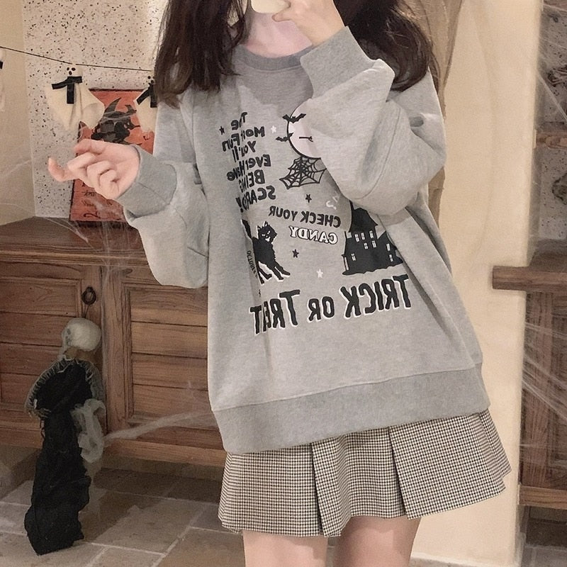 Gray Halloween crewneck sweatshirt styled with a small-check pleated skirt, with the reflected witch-and-castle artwork visible on the front.