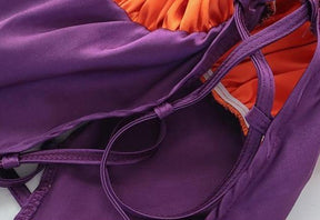 Orange and purple Halloween bodysuit with ruffled trim, a bat neckline accent, halter ties, and lace-up sides