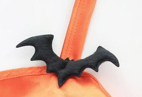 Close-up of a black bat-shaped accent attached where the orange halter strap meets the lingerie top, with the strap stitching visible.