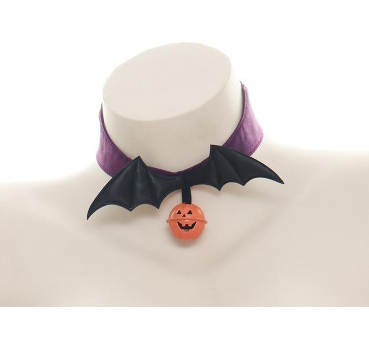 Close front view of the Purple Bat Wings Halloween choker on a display bust, with the orange pumpkin charm hanging below the wing tips.