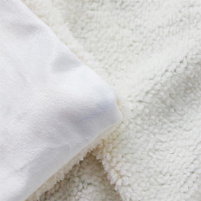 Detail of the blanket's smooth pale reverse side of the printed face beside the sherpa fleece layer.