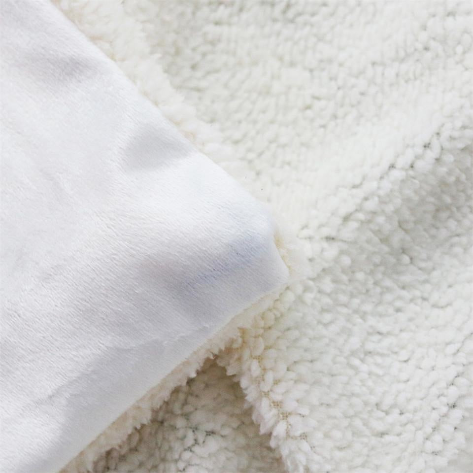 Detail of the blanket's smooth pale reverse side of the printed face beside the sherpa fleece layer.
