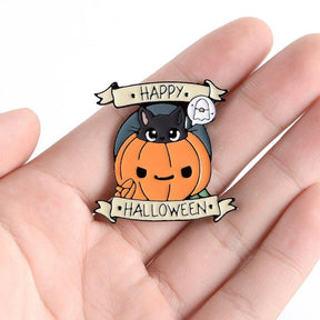 Black cat and pumpkin Happy Halloween pin resting in an open hand, showing the orange face, tiny ghost and banner lettering.