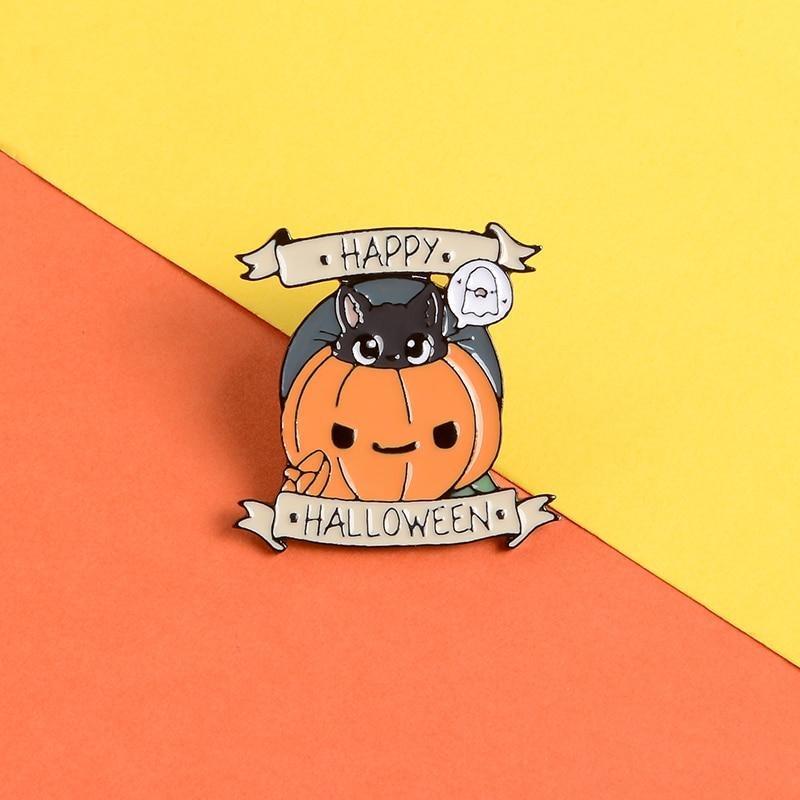 Happy Halloween enamel pin with a black cat, pumpkin and ghost on a diagonally divided orange-and-yellow background.