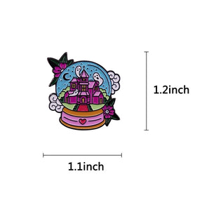 Measurement guide for the pastel haunted castle snowglobe enamel pin, marked 1.2 inches high and 1.1 inches wide.