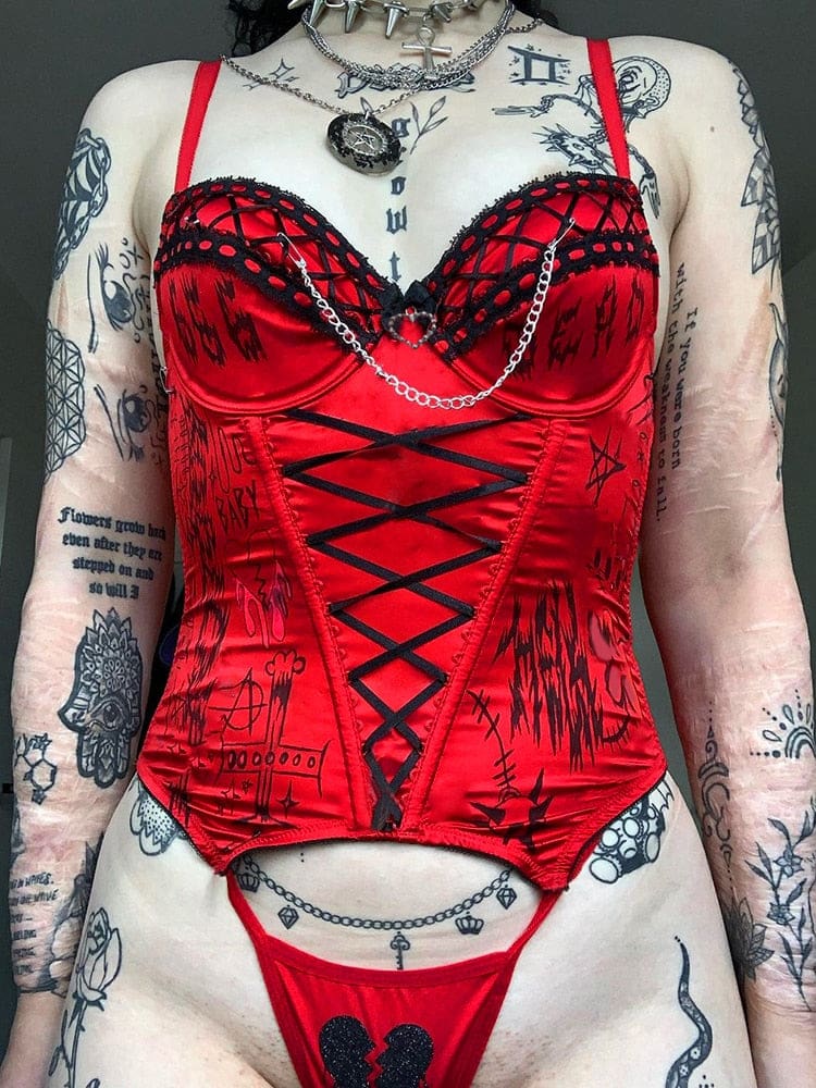 Front view of the red bustier and matching briefs, showing the long black ribbon lacing and broken-heart detail on the briefs.