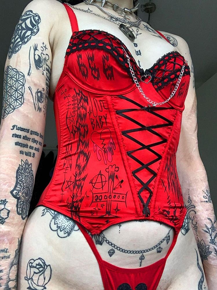 Angled view of the matching red bustier and briefs with black trim and chains, worn beneath layered styling necklaces.