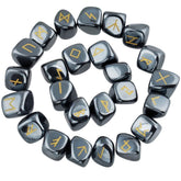 Hematite rune stones arranged in a circle, with dark metallic grey polished surfaces and gold-coloured characters. The set includes a blank stone.
