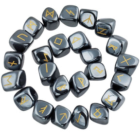Hematite rune stones arranged in a circle, with dark metallic grey polished surfaces and gold-coloured characters. The set includes a blank stone.