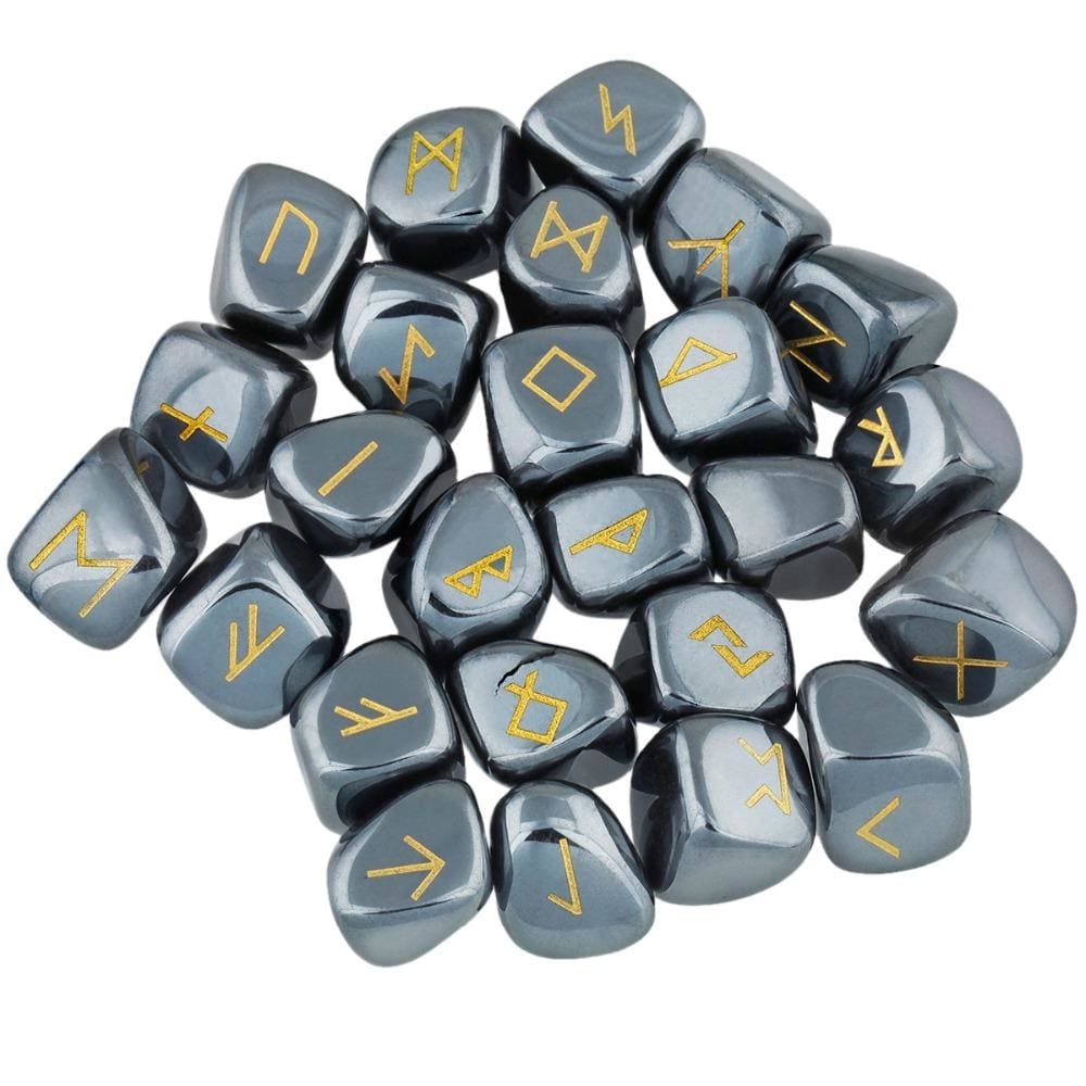 A loose pile of hematite rune stones with dark metallic grey surfaces, rounded edges and gold-coloured rune marks visible across the top.