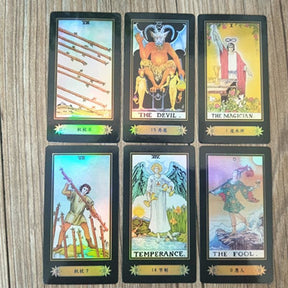 Six holographic tarot cards laid on wood, showing detailed figures and rainbow reflections across the illustrated faces.