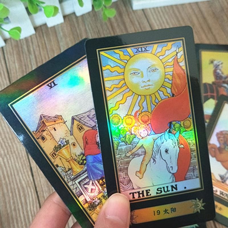 The Sun and The Tower tarot cards held close to the camera, with bright rainbow reflections across the illustrated scenes.