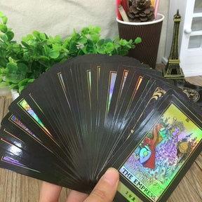 A wide fan of holographic tarot cards held in one hand, showing rainbow highlights and multiple illustrated scenes.