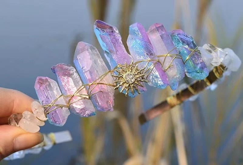 Iridescent crystal tiara with a pointed gold-tone sunburst emblem and rainbow colours across the tall crystal surfaces.