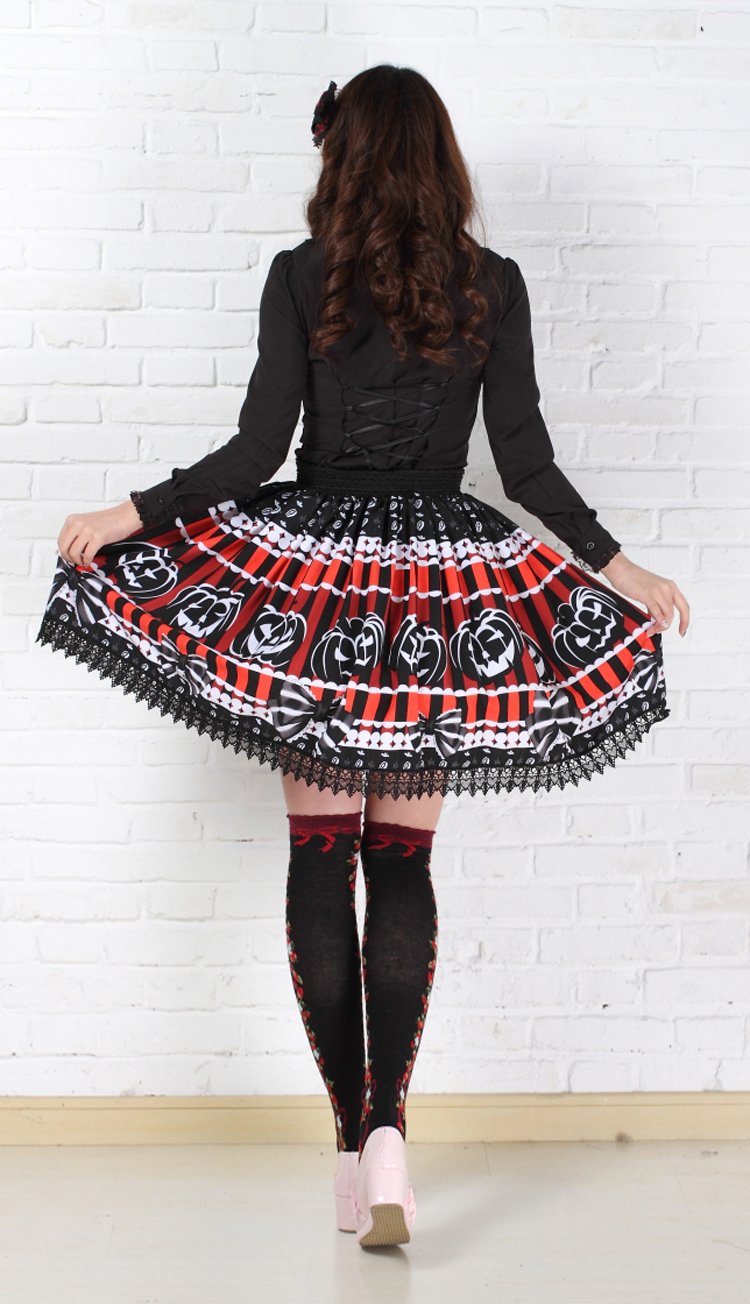 Rear outfit view of the red and black jack-o-lantern skirt held out at both sides, showing the continuing pumpkin print, bow illustrations and black lace edging.