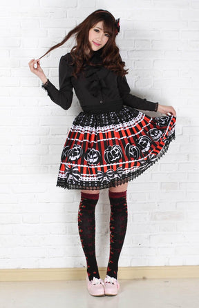 Full outfit view of the striped pumpkin skirt with a black blouse, patterned knee socks and pale shoes. One side of the skirt is lifted to show the printed border and lace hem.