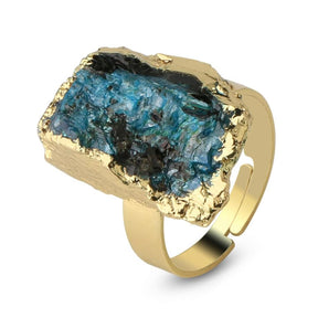 Angled close view of a blue-green kyanite ring with a rough striated surface and gold-tone setting.