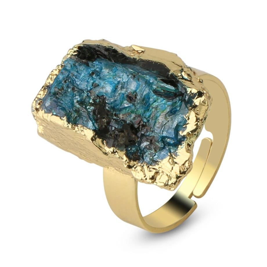 Angled close view of a blue-green kyanite ring with a rough striated surface and gold-tone setting.