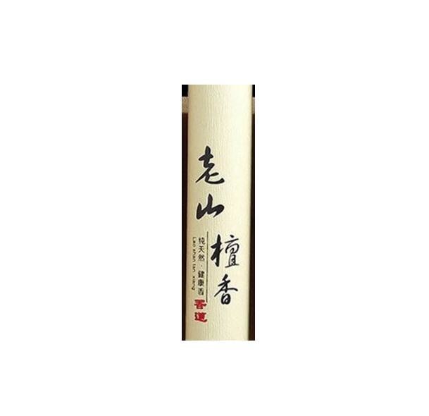 Close view of the pale Laoshan sandalwood incense tube, showing vertical Chinese lettering and a small red seal.