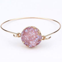 Pale lilac druzy quartz cuff bracelet with its gold-tone hook fastening open beside the circular stone face.